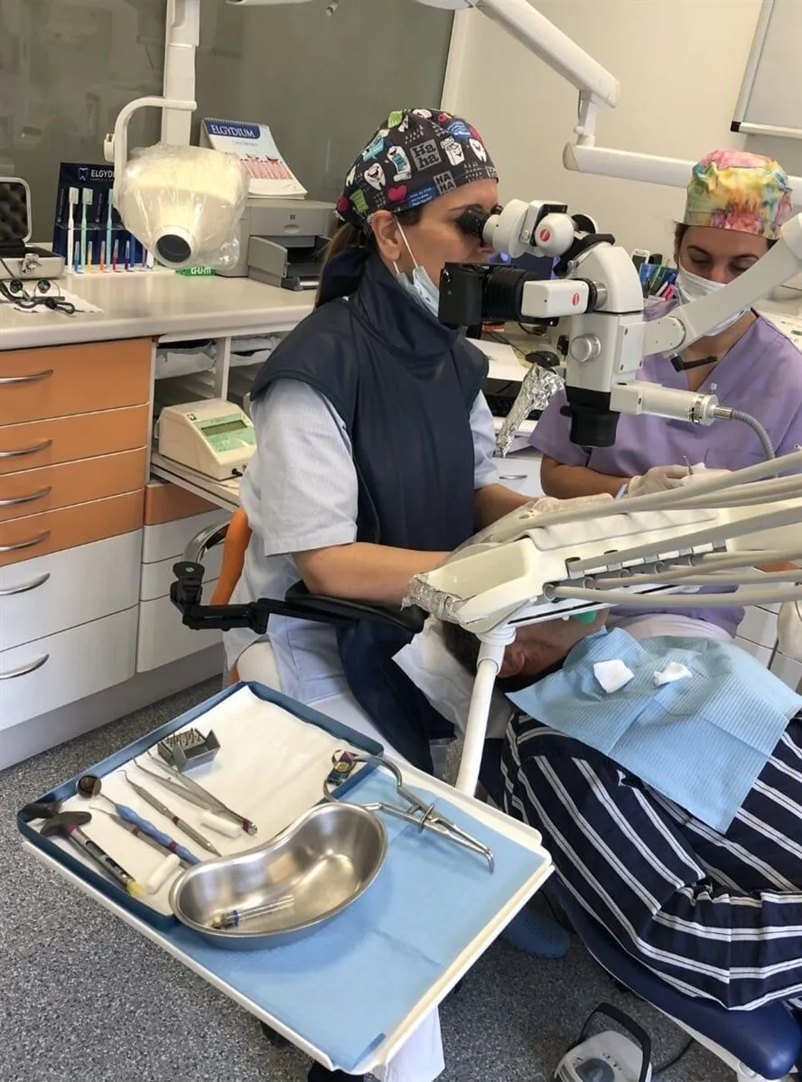 Médica dentista a tratar um paciente com microscópio cirúrgico