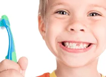 Criança sorridente com escova de dentes